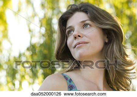 Stock Photograph - Young woman looking away serenely, portrait. Fotosearch