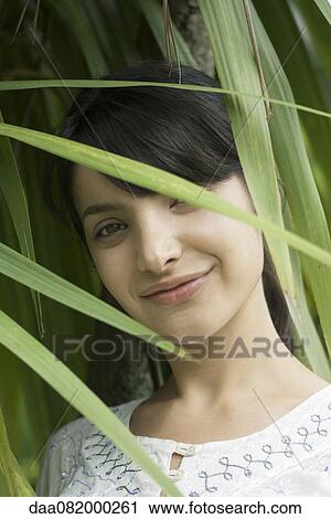 Young woman looking through foliage, portrait View Large Photo Image Stock Image - Young woman looking through foliage, portrait. Fotosearch