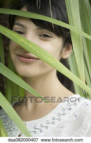 Young woman looking through foliage, portrait View Large Photo Image Stock Photo - Young woman looking through foliage, portrait. Fotosearch