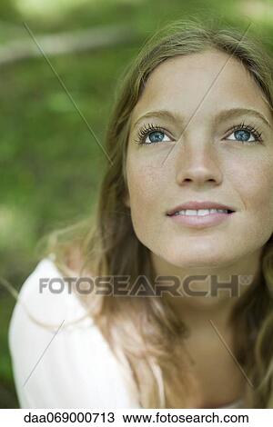 Stock Image - Young woman looking up, portrait. Fotosearch
