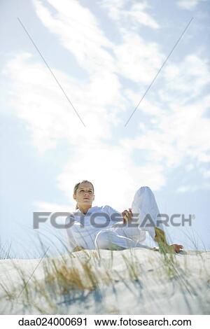 Young woman lounging on dune View Large Photo Image Stock Image - Young woman lounging on dune. Fotosearch