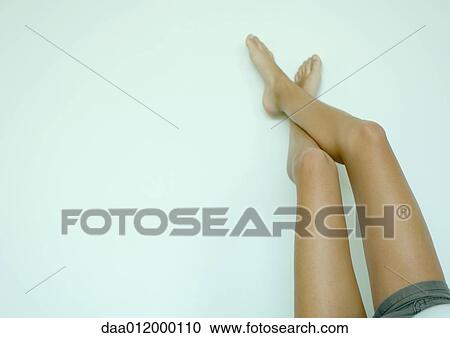 Stock Image - Young woman lying down with legs up, low section. Fotosearch