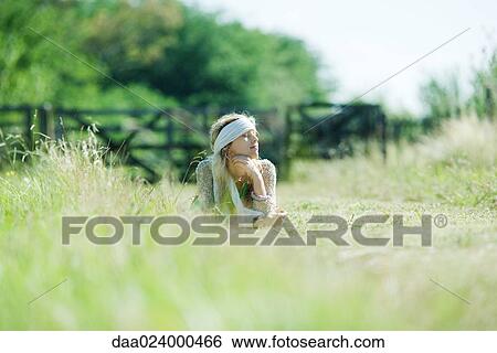 Young woman lying in field, eyes closed View Large Photo Image Stock Photograph - Young woman lying in field, eyes closed. Fotosearch