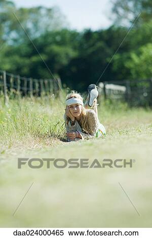Stock Photography - Young woman lying in field, smiling at camera. Fotosearch