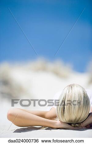 Young woman lying on beach, cropped view of hands behind head View Large Photo Image Stock Photograph - Young woman lying on beach, cropped view of hands behind head. Fotosearch