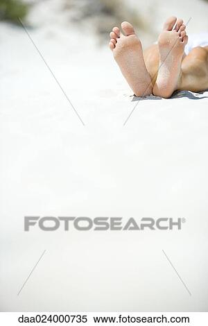 Stock Photography - Young woman lying on beach, cropped view of feet. Fotosearch