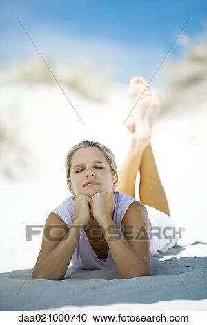 Young woman lying on beach, leaning on elbows, eyes closed View Large Photo Image Stock Image - Young woman lying on beach, leaning on elbows, eyes closed. Fotosearch