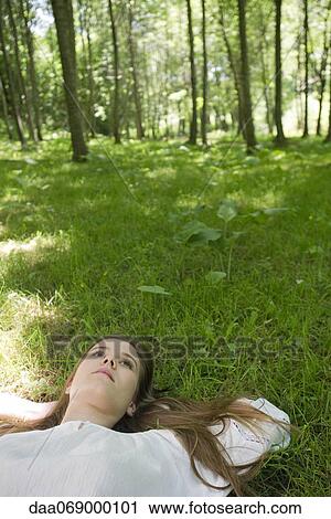 Young woman lying on grass daydreaming View Large Photo Image Stock Image - Young woman lying on grass daydreaming. Fotosearch