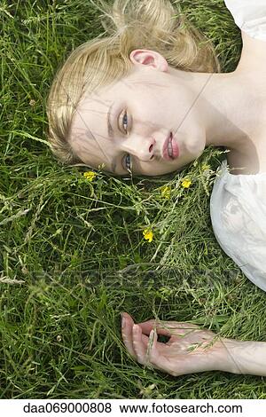 Young woman lying on grass View Large Photo Image Stock Photo - Young woman lying on grass. Fotosearch