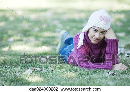 Young woman lying on grass, wearing knit hat and sweater View Large Photo Image Stock Image - Young woman lying on grass, wearing knit hat and sweater. Fotosearch