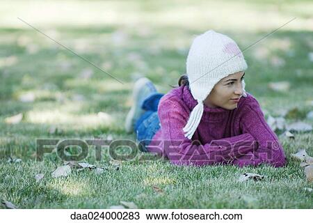 Young woman lying on grass, wearing knit hat and sweater, looking away View Large Photo Image Stock Image - Young woman lying on grass, wearing knit hat and sweater, looking away. Fotosearch