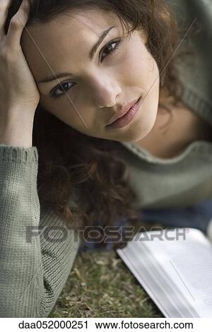 Young woman lying on ground with book, portrait View Large Photo Image Stock Image - Young woman lying on ground with book, portrait. Fotosearch