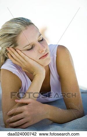 Young woman lying on sand, leaning on elbow, eyes closed View Large Photo Image Stock Image - Young woman lying on sand, leaning on elbow, eyes closed. Fotosearch
