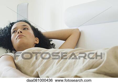 Young woman lying on sofa, looking away in thought View Large Photo Image Stock Photograph - Young woman lying on sofa, looking away in thought. Fotosearch