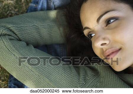 Young woman lying with hands behind head, daydreaming View Large Photo Image Stock Photography - Young woman lying with hands behind head, daydreaming. Fotosearch