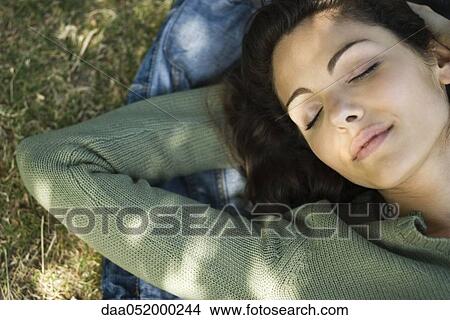 Picture - Young woman napping on grass. Fotosearch