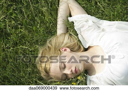 Stock Photo - Young woman napping on grass. Fotosearch