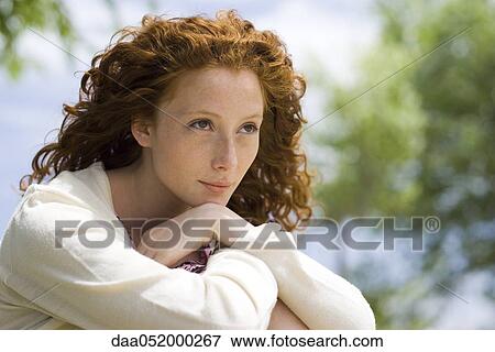 Young woman outdoors, looking away in thought View Large Photo Image Stock Photo - Young woman outdoors, looking away in thought. Fotosearch