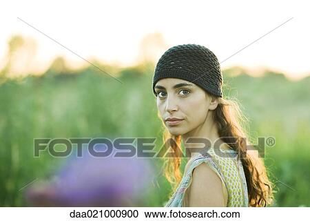 Young woman outdoors, looking over shoulder at camera View Large Photo Image Stock Image - Young woman outdoors, looking over shoulder at camera. Fotosearch