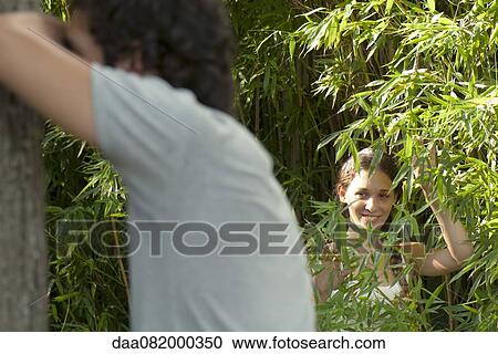 Stock Image - Young woman playing hide-and-seek. Fotosearch