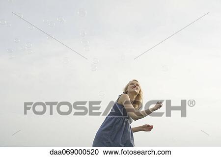 Young woman playing with bubbles outdoors View Large Photo Image Stock Image - Young woman playing with bubbles outdoors. Fotosearch