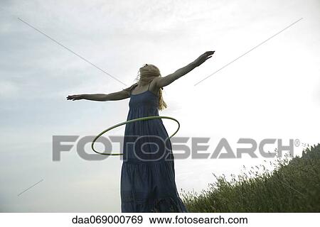 Young woman playing with plastic hoop outdoors View Large Photo Image Stock Photo - Young woman playing with plastic hoop outdoors. Fotosearch