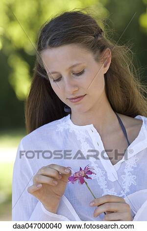 Young woman plucking petals from flower View Large Photo Image Stock Image - Young woman plucking petals from flower. Fotosearch
