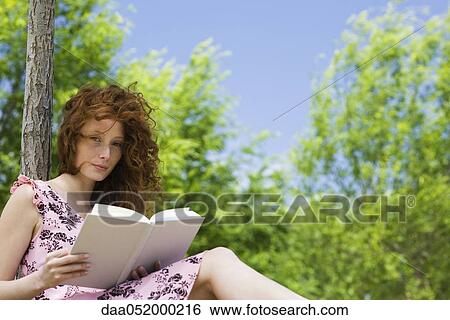 Stock Photograph - Young woman reading outdoors, portrait. Fotosearch