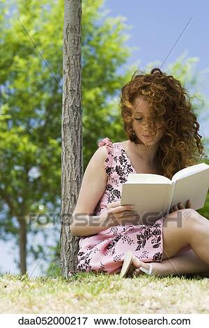 Young woman reading outdoors View Large Photo Image Stock Photo - Young woman reading outdoors. Fotosearch