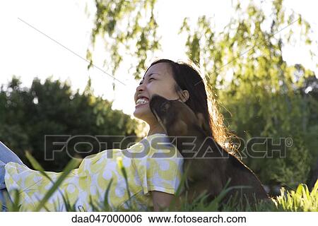 Young woman reclining in grass with puppy, laughing View Large Photo Image Stock Photograph - Young woman reclining in grass with puppy, laughing. Fotosearch