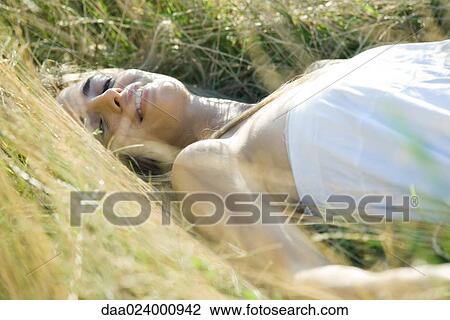 Young woman reclining in tall grass, smiling at camera View Large Photo Image Stock Image - Young woman reclining in tall grass, smiling at camera. Fotosearch