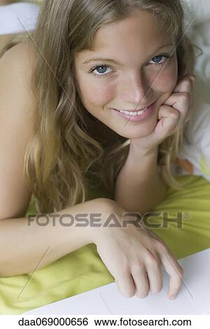 Stock Photograph - Young woman relaxing in bed, portrait. Fotosearch