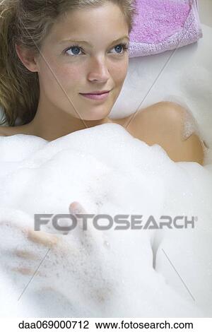 Stock Image - Young woman relaxing in bubble bath. Fotosearch