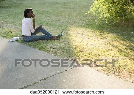 Young woman relaxing in park using cell phone View Large Photo Image Stock Image - Young woman relaxing in park using cell phone. Fotosearch