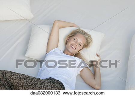 Young woman relaxing on bed View Large Photo Image Stock Image - Young woman relaxing on bed. Fotosearch