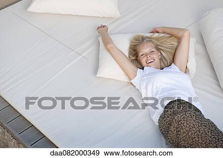 Young woman relaxing on bed View Large Photo Image Stock Photo - Young woman relaxing on bed. Fotosearch