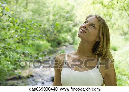 Young woman relaxing outdoors, looking up in thought View Large Photo Image Stock Image - Young woman relaxing outdoors, looking up in thought. Fotosearch