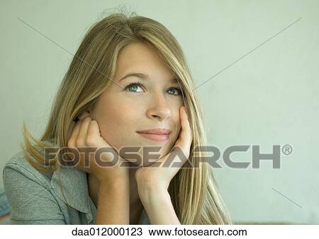 Stock Image - Young woman resting head in hands and looking away. Fotosearch