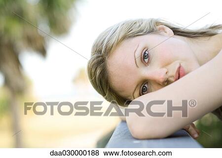 Young woman resting head on arms, looking at camera View Large Photo Image Stock Photo - Young woman resting head on arms, looking at camera. Fotosearch