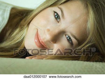 Stock Photo - Young woman resting head on hand, smiling, close-up. Fotosearch