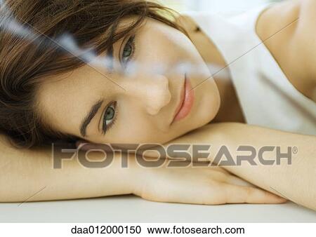 Young woman resting head on hands, looking at smoking incense View Large Photo Image Stock Image - Young woman resting head on hands, looking at smoking incense. Fotosearch
