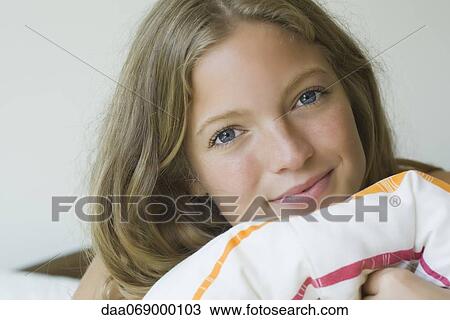 Stock Image - Young woman resting head on pillow, portrait. Fotosearch