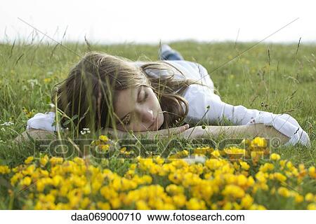 Stock Image - Young woman resting on meadow. Fotosearch