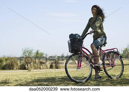 Young woman riding bicycle in park View Large Photo Image Stock Photo - Young woman riding bicycle in park. Fotosearch