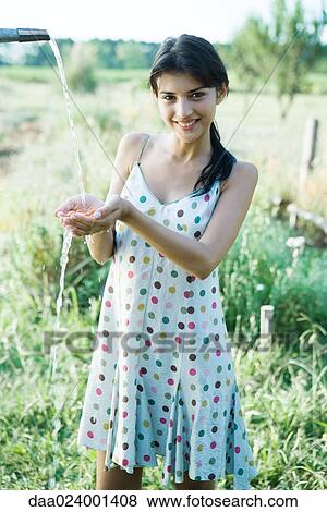 Stock Photo - Young woman rinsing off handful of cherry tomatoes outdoors. Fotosearch