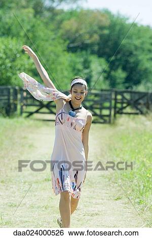 Young woman running along rural path, arm raised View Large Photo Image Stock Photograph - Young woman running along rural path, arm raised. Fotosearch