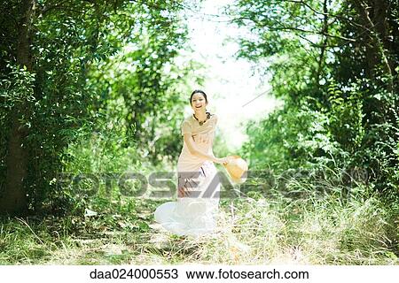 Young woman running in woods, holding sunhat, smiling at camera View Large Photo Image Stock Image - Young woman running in woods, holding sunhat, smiling at camera. Fotosearch