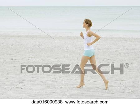 Stock Photo - Young woman running on beach. Fotosearch