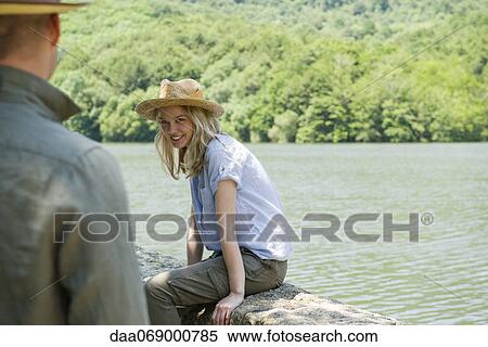 Young woman sitting by lake, man in foreground View Large Photo Image Stock Photography - Young woman sitting by lake, man in foreground. Fotosearch