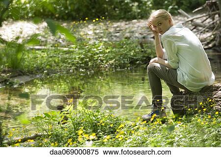 Young woman sitting by river View Large Photo Image Stock Photography - Young woman sitting by river. Fotosearch